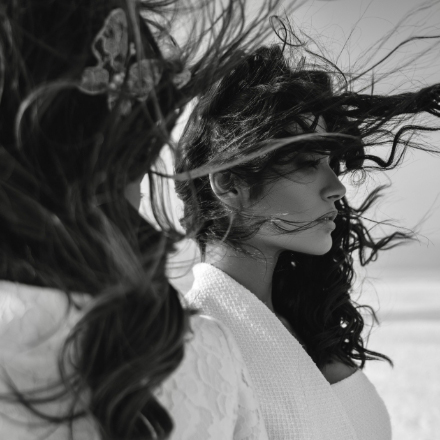 Woman with flowing hair in a casual hairstyle, showcasing the beauty of African braiding against a beach backdrop.